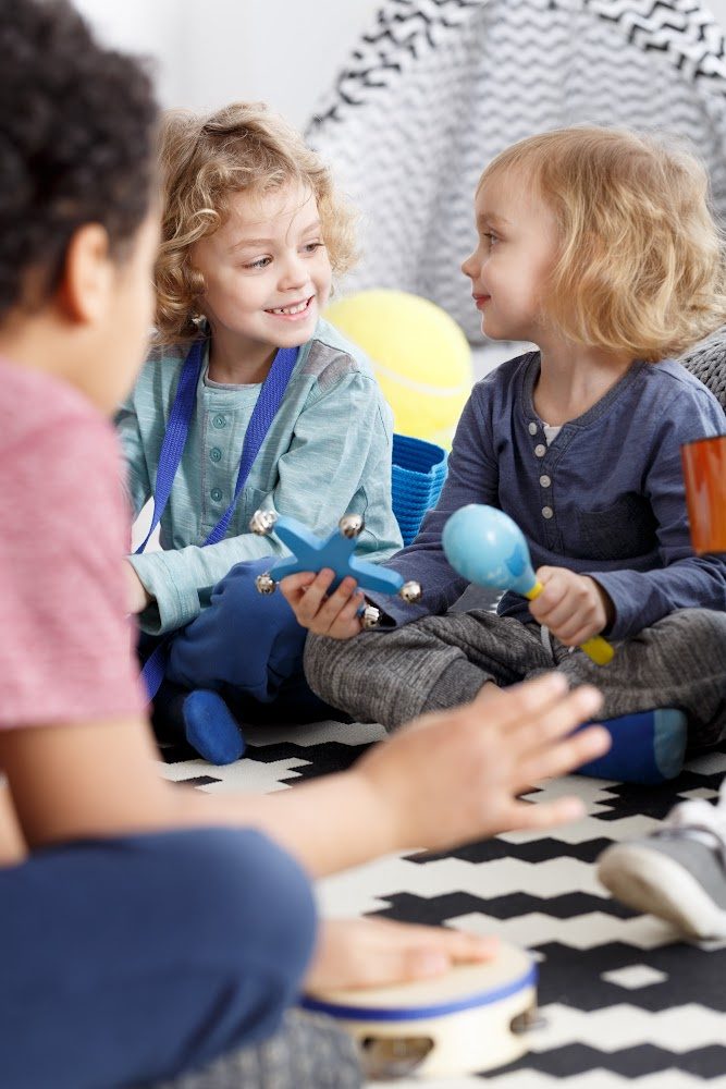 Children sitting on a rug playing with toys