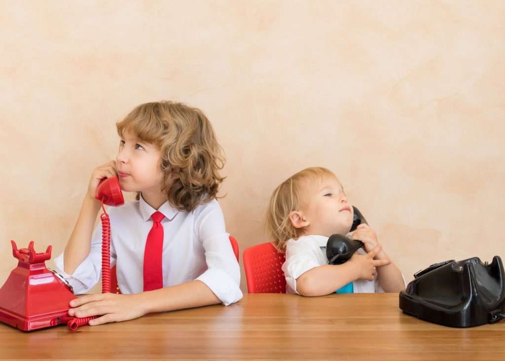 Kids pretending to take phone calls at a desk